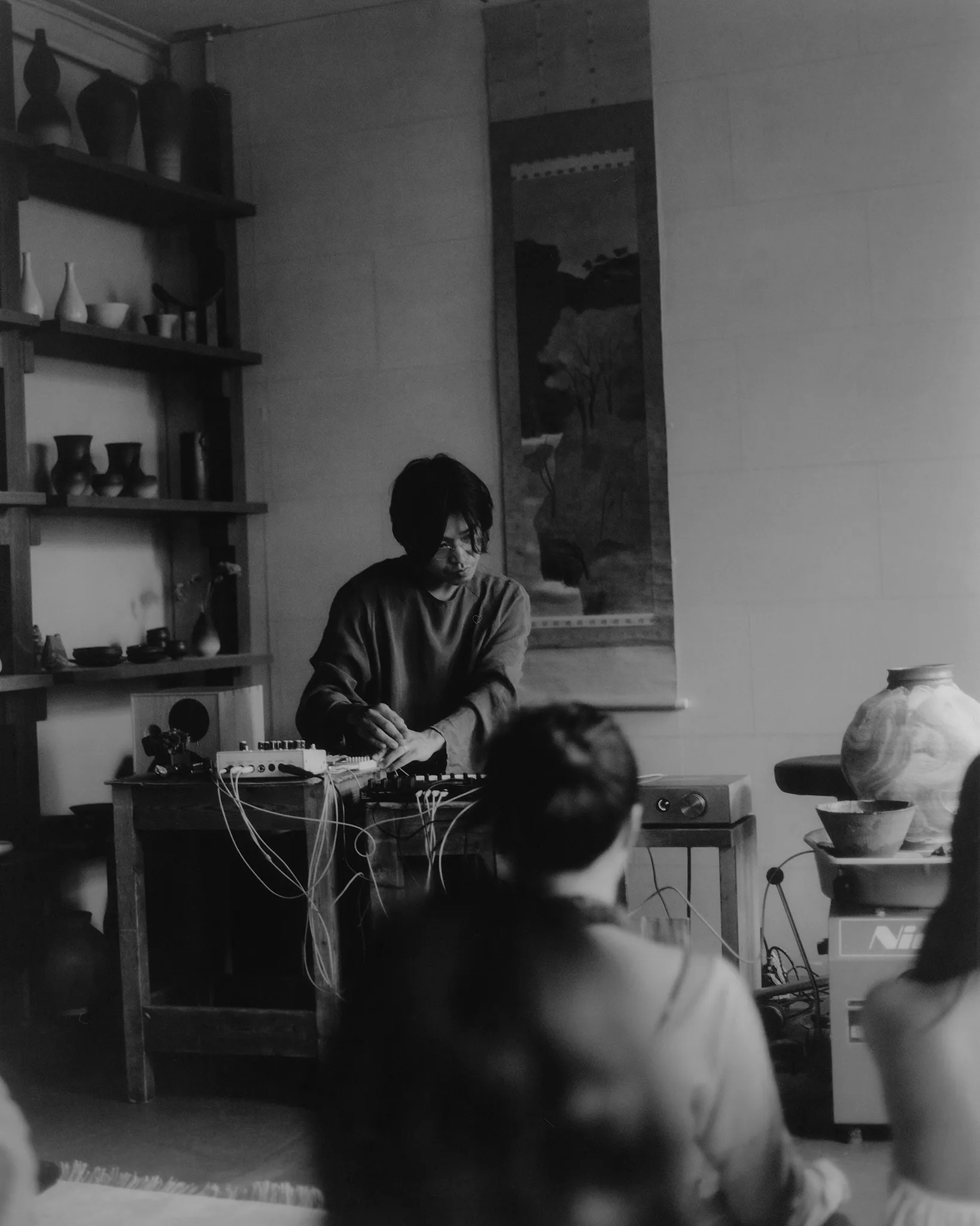 The performance seen through the audience, and Huh Namhoon at his equipment among the ceramics